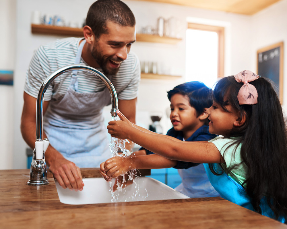 Father and children washing their hands at the sink
